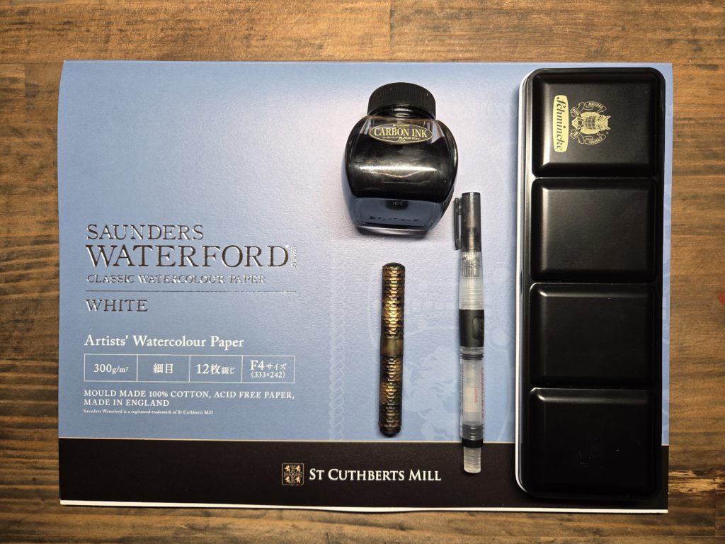 洋伯が絵を描くときに使っている透明水彩と万年筆とインクと筆と紙の写真