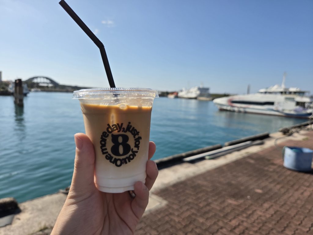 カフェラテをもって海を見ている写真